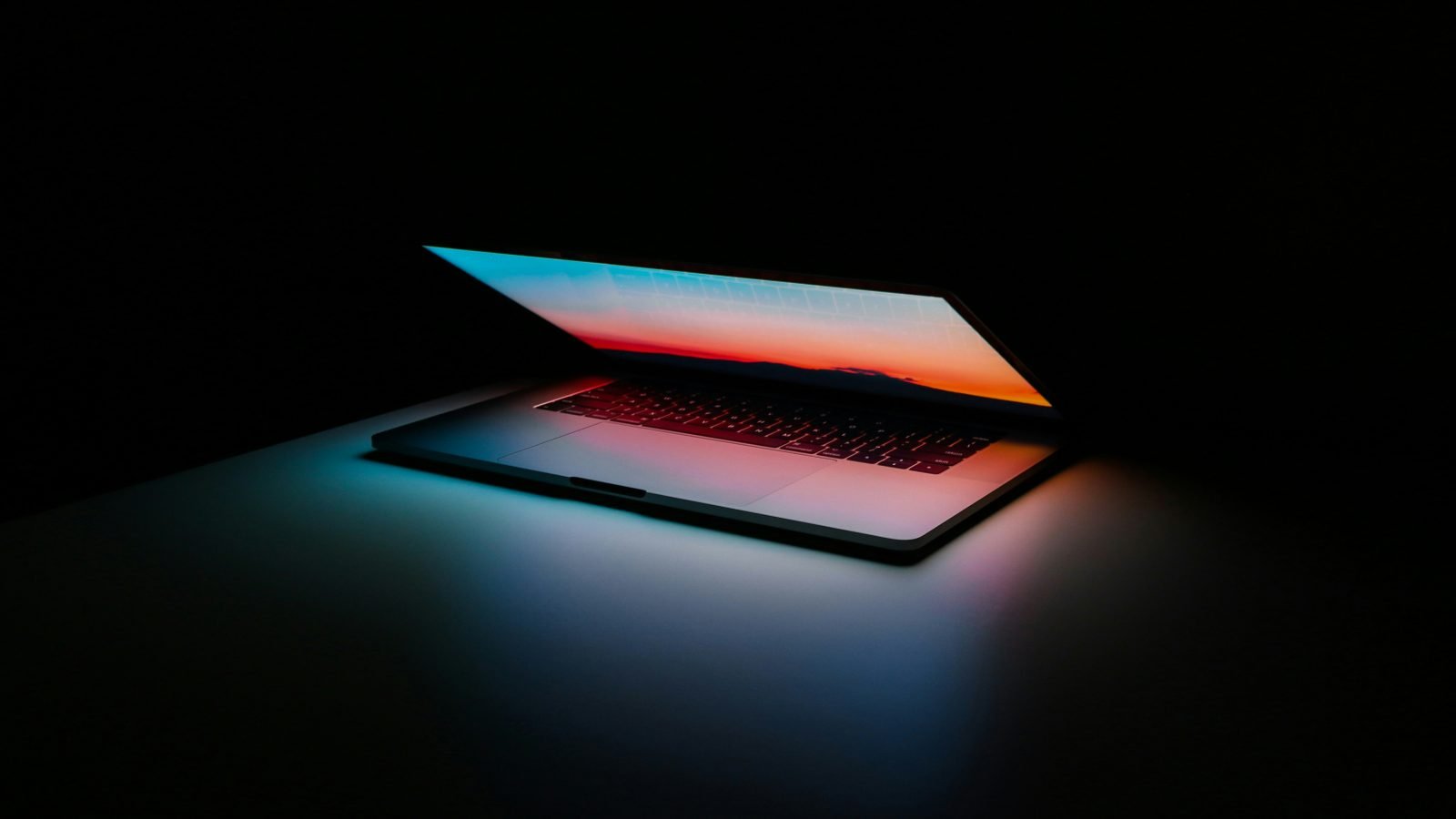 Gray and black laptop displaying a vibrant design canvas, evoking Figma's editor